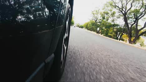 car pov from road facing front right wheel driving down bitumen road down a hill into town