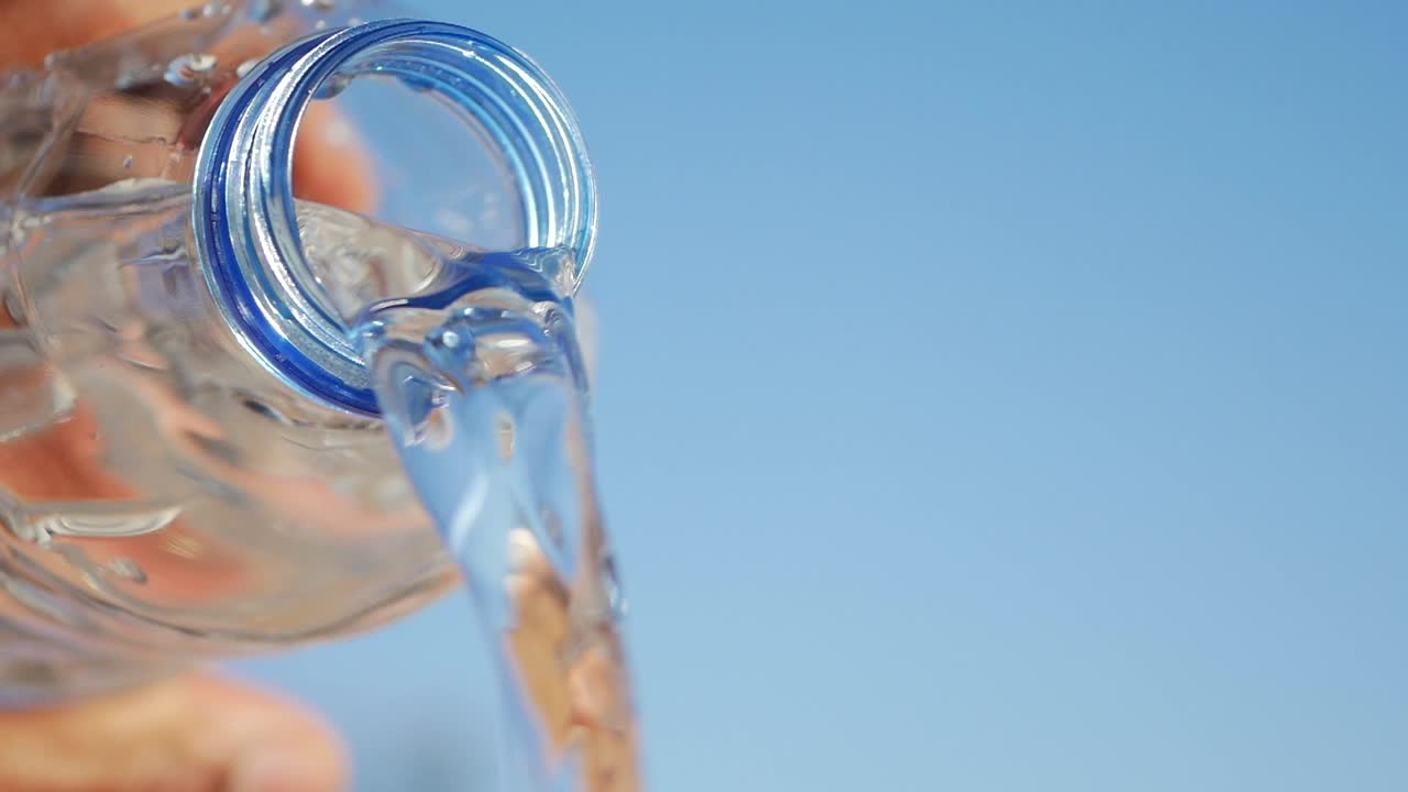 Water pouring from a bottle against a blue sky