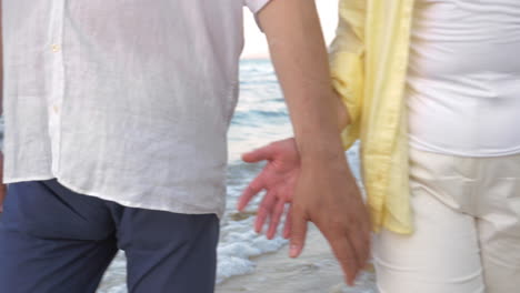 senior couple holding hands during walk on beach