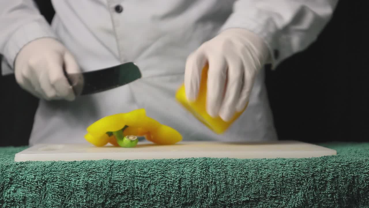 cocinero cortando un pimentón amarillo con un primer plano de fondo negro