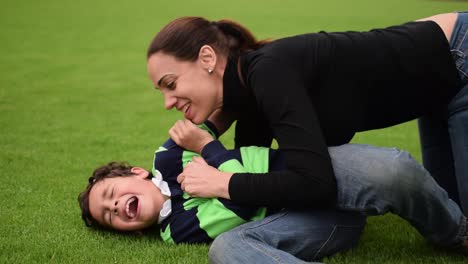loving mother and child playing in the grass, having fun and tickling