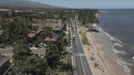 Low-aerial-follows-light-traffic-on-Kihei-beach-road-past-palm-trees