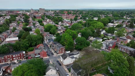aerial view of lancaster, pa in spring. lush trees line charming residential streets, historic brick homes, and blooming greenery create a peaceful small-town american atmosphere. downtown in distance