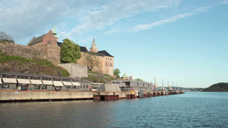 Un-Lapso-De-Tiempo-De-Vista-Panorámica-Del-Fiordo-En-Oslo-Con-Un-Castillo-Sentado-En-El-Fondo-Frente-A-Una-Colina-Azul