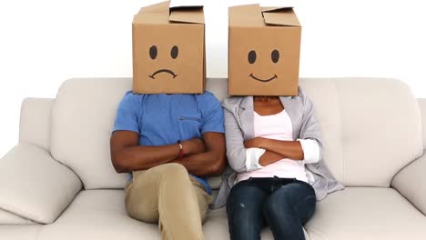 partner sitzen auf dem sofa mit emotikon-boxen auf ihren köpfen