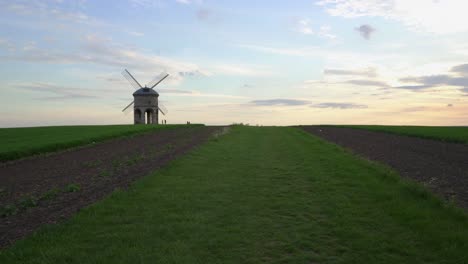 chesterton windmill, an old stone windmill, across a field on a summer evening with distant people watching the setting sun, near leamington spa, warwickshire, england