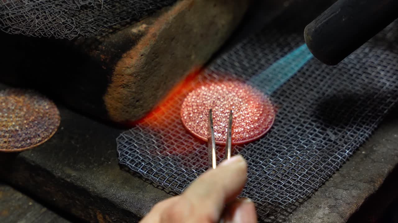 Close-up video showing a silversmith heating metal with a torch while crafting intricate jewelry in Celuk Village, Bali, Indonesia — famous for its traditional silver artistry and handmade crafts