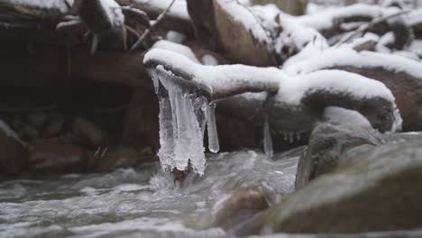 ice hanging on a stick above flowing stream of water