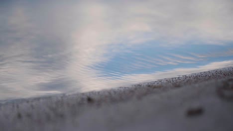 Close-up-shot-of-soft-waves-hitting-shore-on-the-lake,-soft-ripple-on-the-water-surface