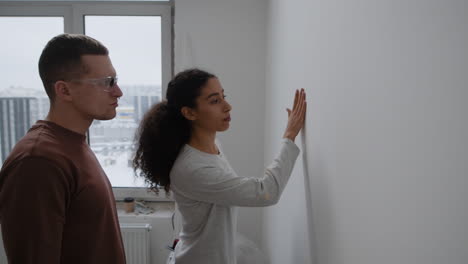 young couple doing home improvement: sanding and inspecting walls