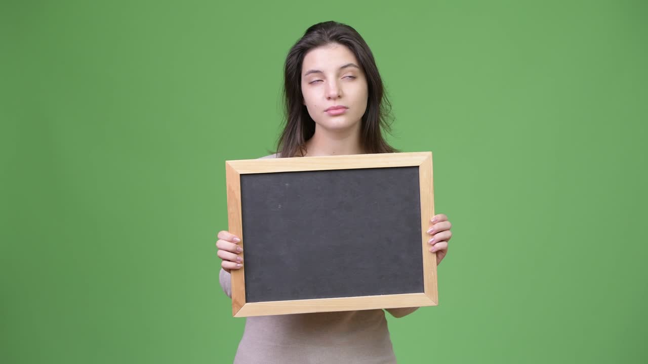 Young beautiful woman thinking while holding blackboard