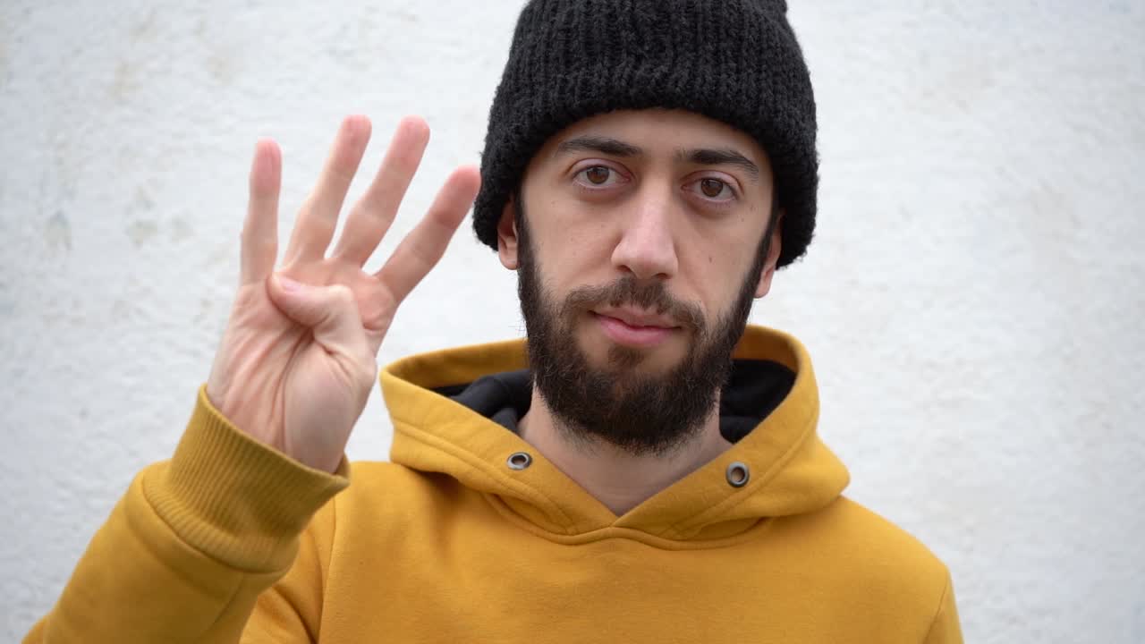Young Man In Beanie Hat And Jacket Counting One To Five With Right Hand. close up