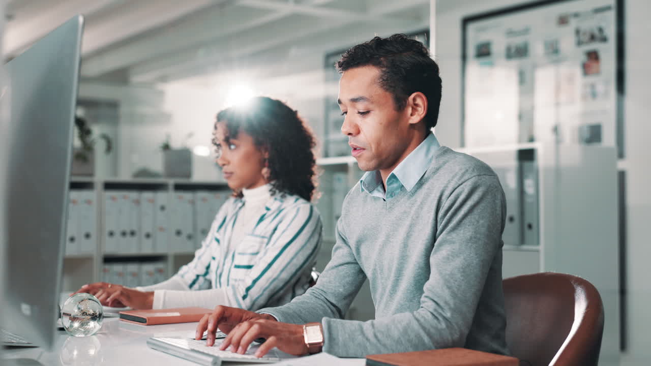 Two people working on computers in an office setting