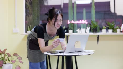 using a credit card to make an e-banking payment using laptop technology, a woman customer pays for her purchase in a web retailer.