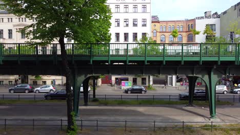 Small-car-parked-on-the-side-of-the-road-in-front-of-the-elevated-train