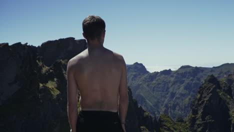 shirtless young man looks out over beautiful volcanic mountain range