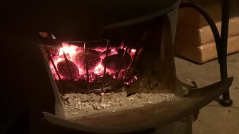 estufa de leña de hierro fundido ardiendo en la cocina de la cabaña de madera al aire libre cerca de los carbones