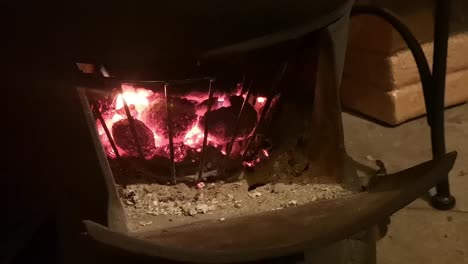 cast iron wood burning stove blazing in outdoor wooden cabin kitchen close up on coals