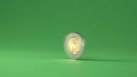 a mexican 5 pesos coin spinning from right to left on a chroma background