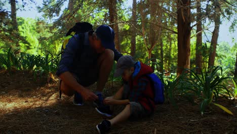 padre ayudando a su hijo a atar el cordón de sus zapatos en el parque