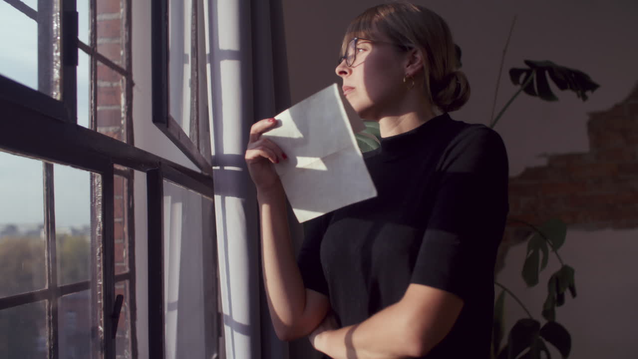 Donna che legge una lettera vicino alla finestra