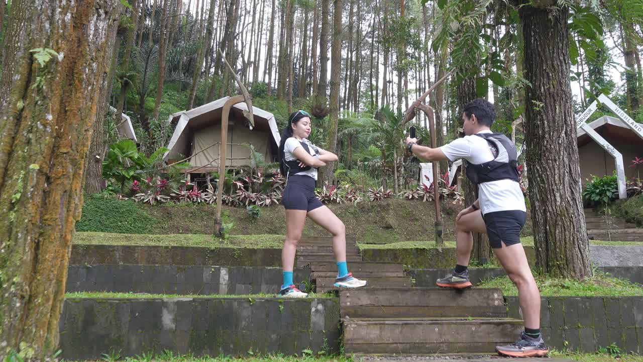 Asian couple taking photos during outdoor adventure in forest