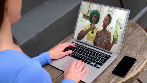 mujer caucásica en casa usando una computadora portátil haciendo una videollamada en el día de san patricio
