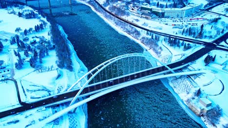 Los-Pájaros-Aéreos-De-Invierno-De-4k-Ven-Sobre-El-Puente-De-Arco-Atado-Icónico-Moderno-De-Walter-Dale,-El-Autobús-Escolar-De-Longitud-Completa-ámbar-Se-Acerca-Al-Cruce-Unidireccional-Sobre-El-Río-Saskatchewan-Del-Norte-Que-Se-Refleja-En-El-Agua-1-2