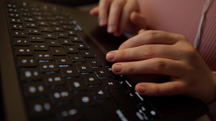 Female hands type on a laptop keyboard at a home desk