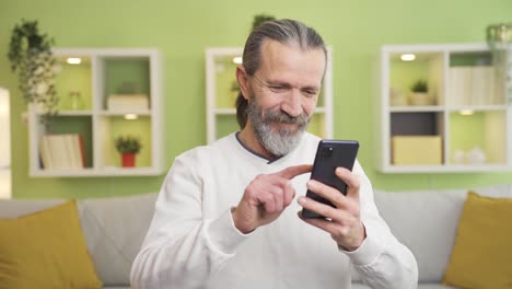 El-Anciano-Que-Mira-El-Teléfono-En-Casa-Se-Emociona-Y-Se-Pone-Triste.