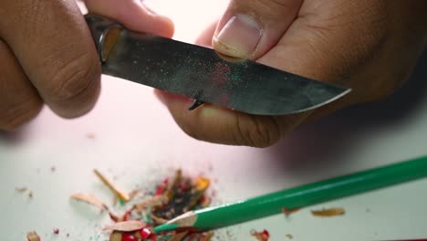 Footage-of-hands-slowly-sharpening-a-pencil-and-some-coloured-pencils-with-a-sharp-knife