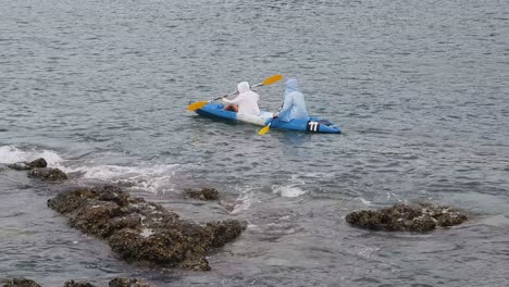 two people kayaking in the ocean near the shore