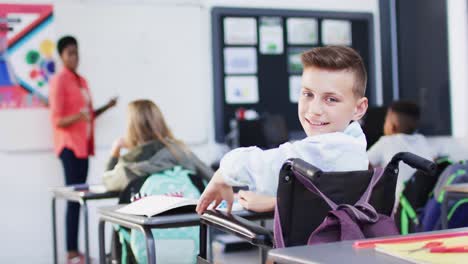 retrato de un escolar caucásico discapacitado feliz y escolares diversos en el aula de la escuela