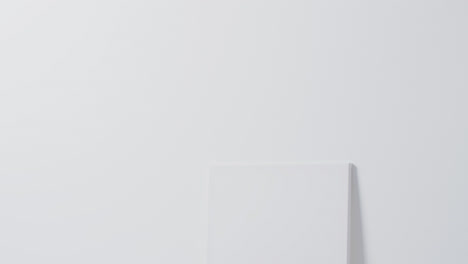 Vertical-video-of-white-canvas-sign-with-copy-space-on-floor-against-white-background