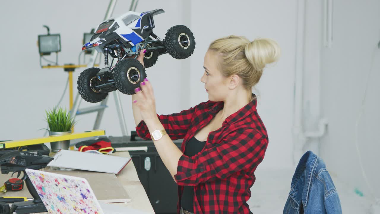 mujer examinando un coche controlado por radio en el taller