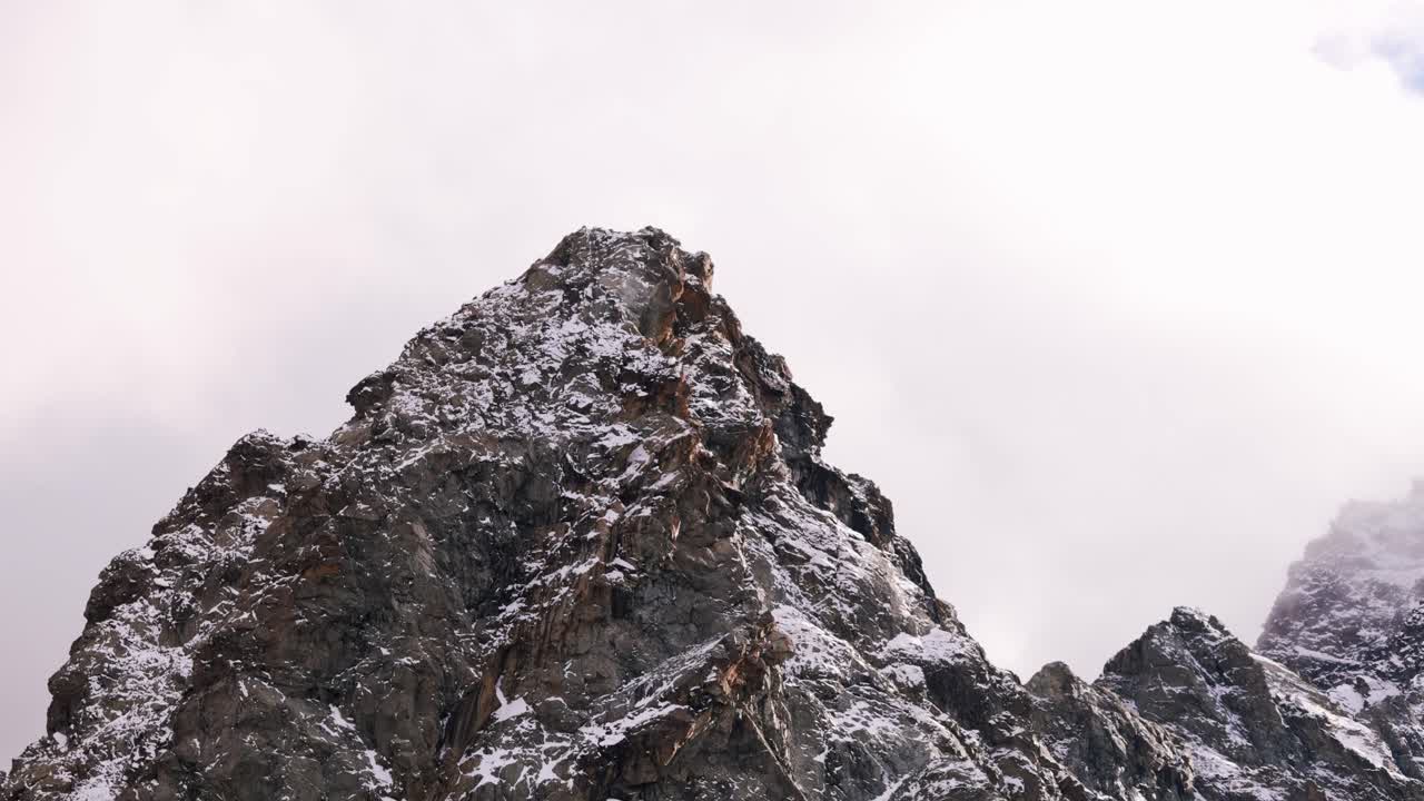 Luftaufnahme der schneebedeckten Valmalenco-Alpen in Italien, wunderschön umrahmt von Wolken und blauem Himmel. Der majestätische Gipfel vermittelt ein Gefühl von Ruhe und Ehrfurcht. Aufsteigende Parallaxenaufnahme