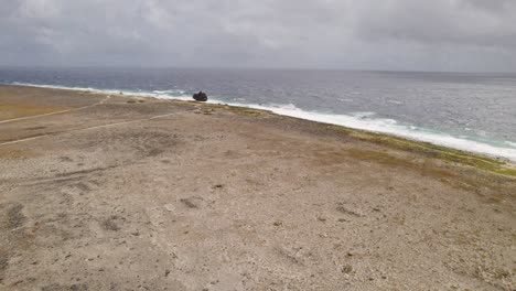 aerial approach to the sandy shore with a rusty shipwreck on top