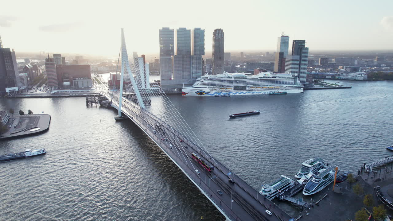 Tranvía y tráfico en el Erasmusbrug cruzando el Nieuwe Maas con el crucero AIDA atracado en la Terminal de Cruceros de Róterdam en Países Bajos