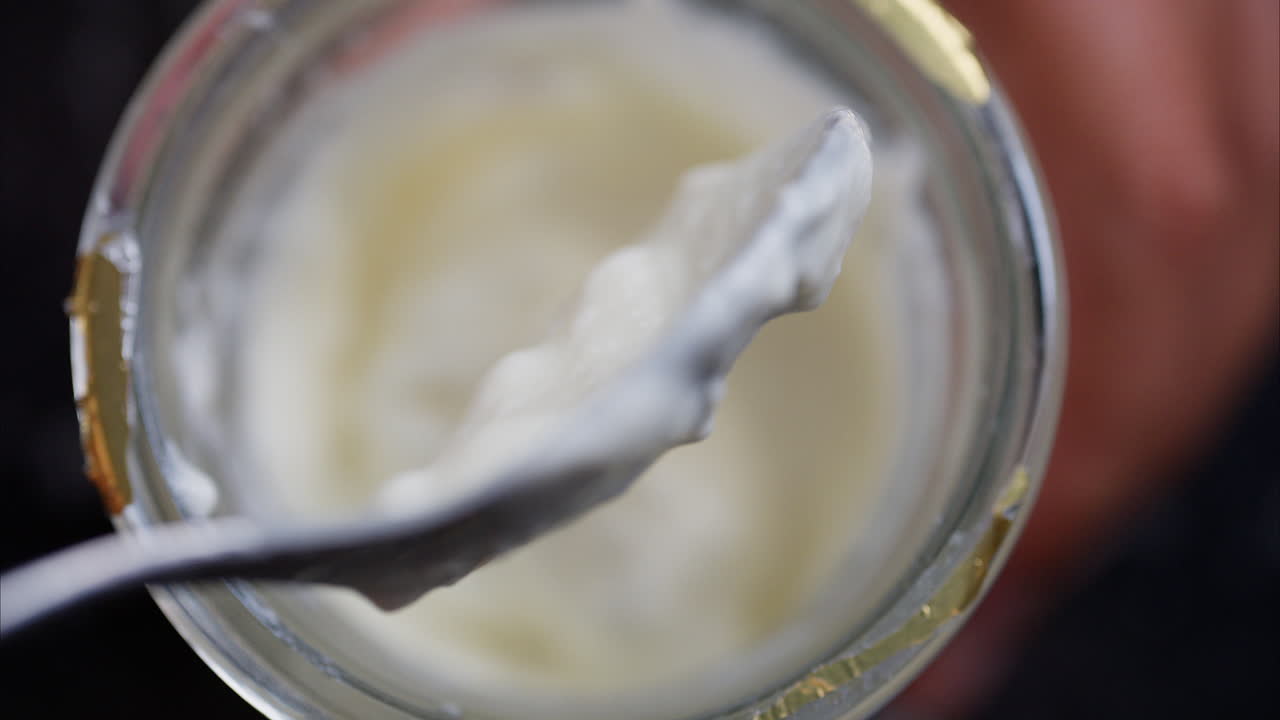 Close up of a white paste being picked up with a spoon from a jar