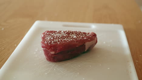 salting a piece of steak tenderloin or filet mignon in preparation for cooking