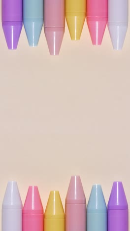 Portrait stop-motion loop of pastel pens forming a top-and-bottom border on beige, large central copy space
