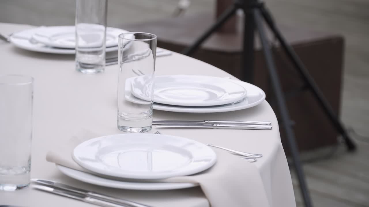 el gerente del banquete pone una servilleta textil bajo un plato blanco. la mujer sirve la mesa.