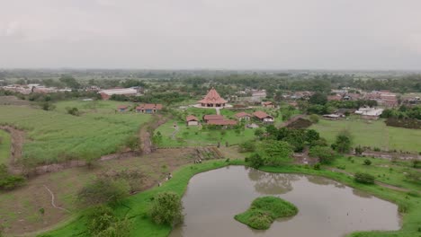 aerial footage showing the pond, birds flying, a group of people walking and the baha’i house of worship in cali, colombia