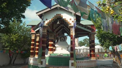 Prayer-flags-swaying-in-wind,-hanged-in-tree-as-camera-tracks-towards-buddhist-temple