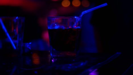 primer plano de un cóctel de alcohol en un vaso en el mostrador de un bar, en un club nocturno. fondo borroso, 4k