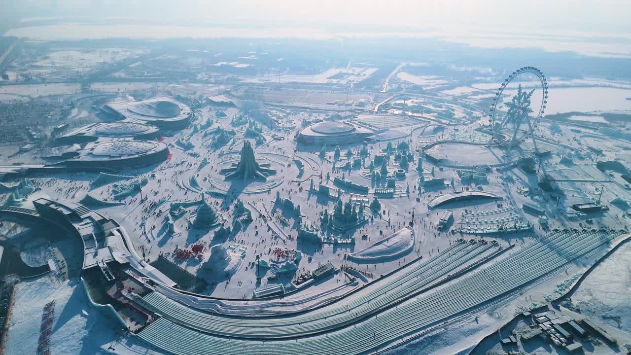 A breathtaking drone shot showcasing the sprawling Harbin Ice and Snow World during the 2025 Ice Festival. The scene features grand ice sculptures, the Snowflake Ferris Wheel, and a winter wonderland.