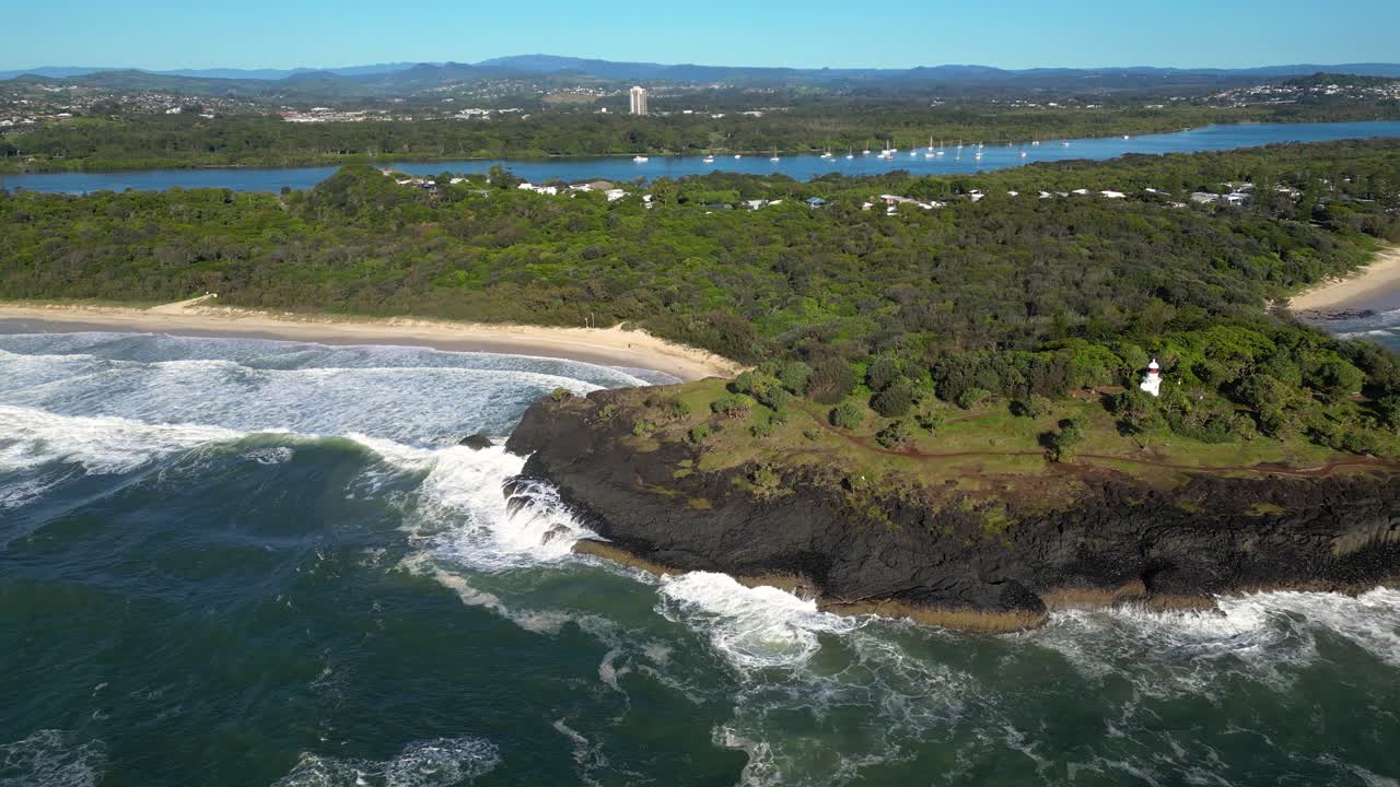 Left to right aerial looking at Fingal Head Lighthouse from over the ocean on a sunny day, Northern New South Wales, Australia.