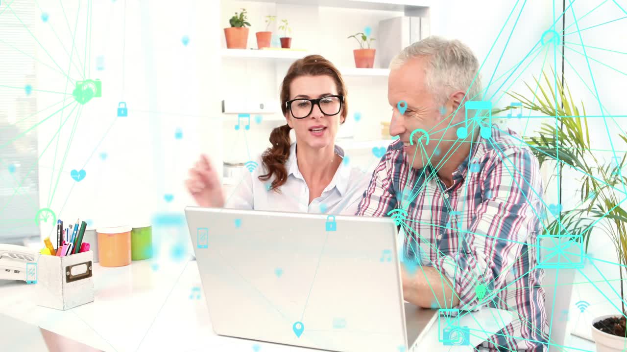 Due globi di icone digitali che ruotano su una coppia anziana caucasica che usa il laptop insieme a casa