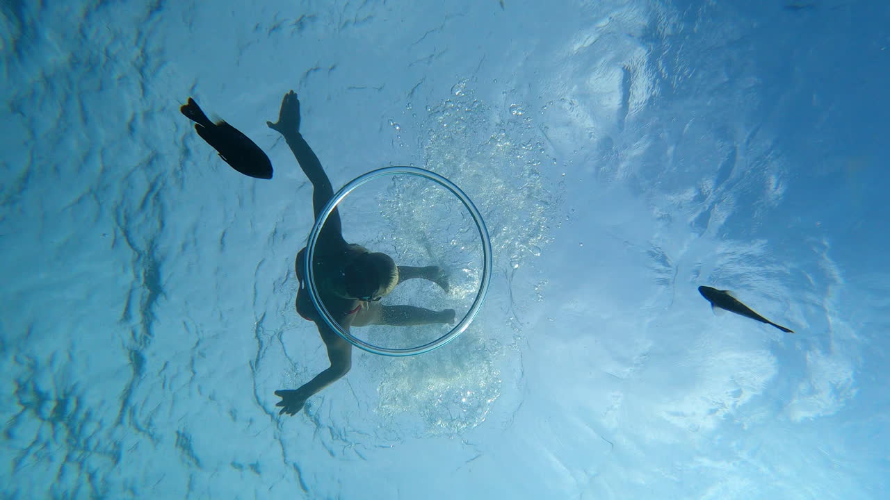 Beautiful female diver swims gracefully through a bubble ring underwater in slow motion
