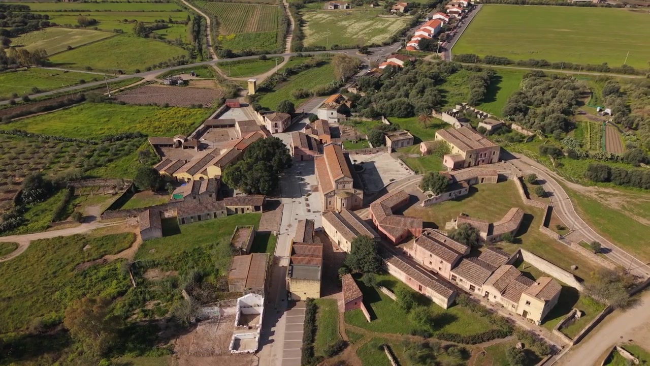 Storica Cattedrale di Santa Maria di Monserrato con edifici del villaggio circostante e terreni agricoli in Sardegna, Italia. Ripresa aerea